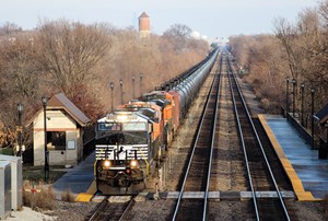 With the Willis Tower (Chicago’s tallest building) barely visible next to the old water tower, a westbound oil train, with a Norfolk Southern unit on the point, passes the Highlands station in Hinsdale, Ill., on Feb. 21, 2015. Photo by David Lassen.